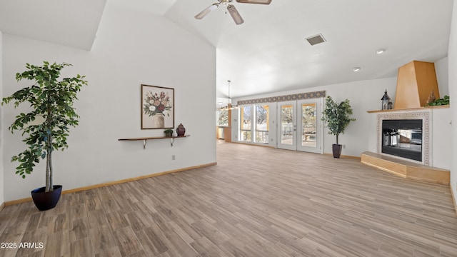 unfurnished living room with a fireplace, light wood-type flooring, ceiling fan with notable chandelier, and vaulted ceiling