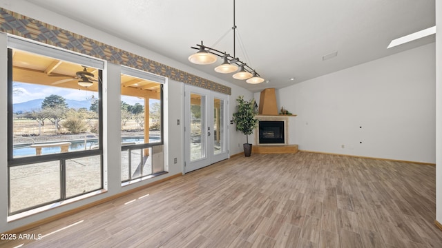 unfurnished living room with hardwood / wood-style floors, ceiling fan, a fireplace, and french doors