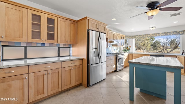 kitchen with light stone countertops, stainless steel appliances, ceiling fan, sink, and light tile patterned flooring