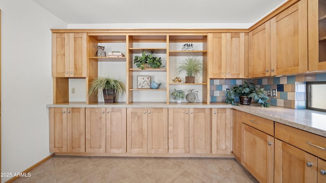 kitchen featuring backsplash, light stone counters, light brown cabinetry, and light tile patterned flooring