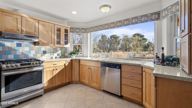 kitchen with light stone countertops, sink, stainless steel appliances, decorative backsplash, and light tile patterned floors