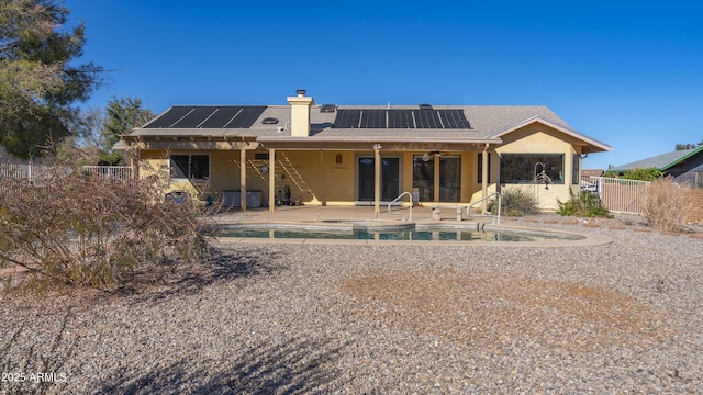 rear view of property with solar panels, a fenced in pool, and a patio