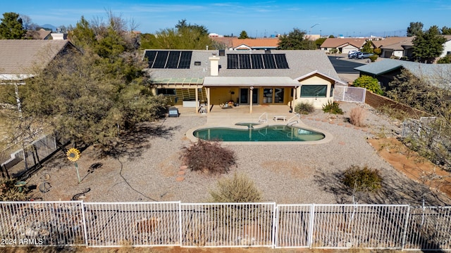 back of house with solar panels, a fenced in pool, and a patio