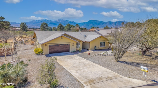 view of front of house with an attached garage, a mountain view, driveway, and stucco siding