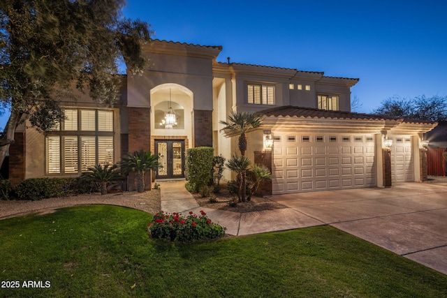 mediterranean / spanish home with a garage, french doors, and a lawn