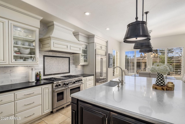 kitchen with sink, custom range hood, decorative backsplash, and premium appliances