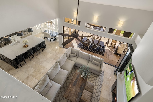 tiled living room with a high ceiling and ceiling fan