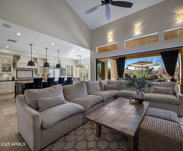 living room with ceiling fan, light tile patterned floors, and a high ceiling