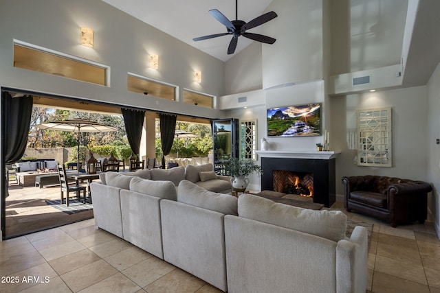 living room with ceiling fan, a healthy amount of sunlight, high vaulted ceiling, and light tile patterned floors