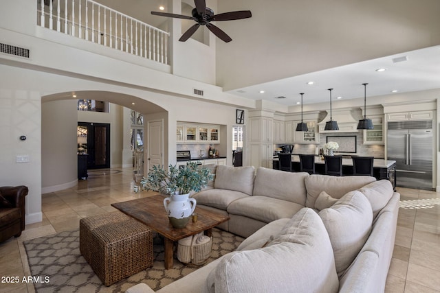 living room featuring a high ceiling, ceiling fan, and light tile patterned floors