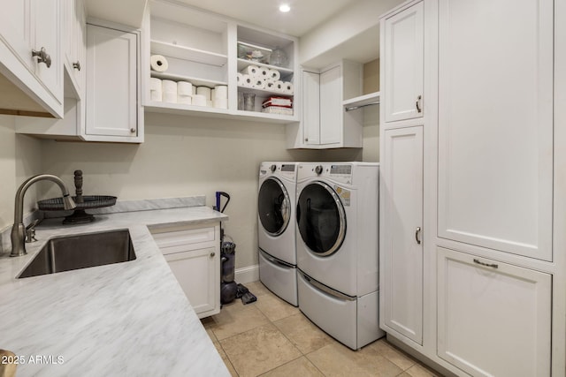 clothes washing area with sink, washer and clothes dryer, light tile patterned flooring, and cabinets