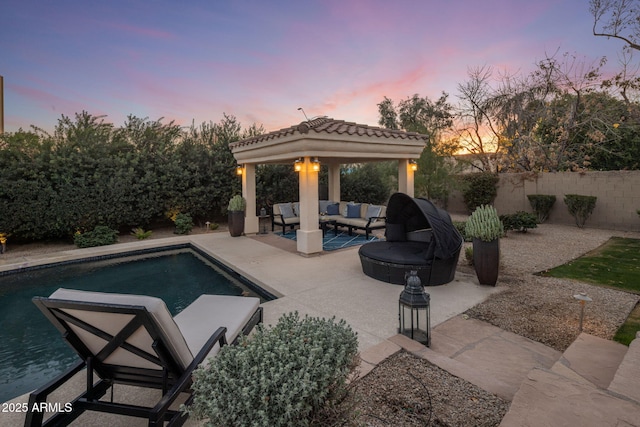 pool at dusk featuring a patio, an outdoor hangout area, and a gazebo