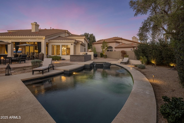 pool at dusk featuring a patio area and area for grilling