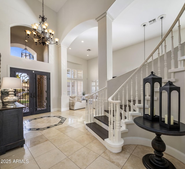 foyer entrance with french doors, a high ceiling, an inviting chandelier, and tile patterned floors