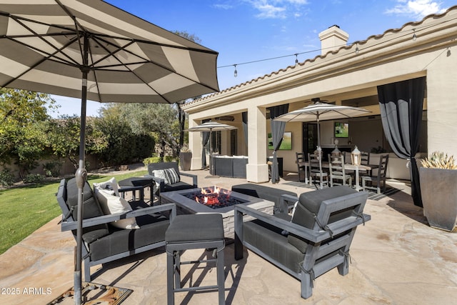 view of patio featuring ceiling fan and an outdoor living space with a fire pit