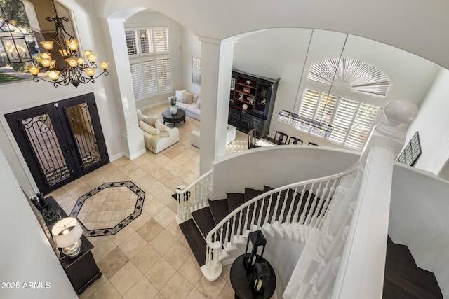 tiled entryway with decorative columns, an inviting chandelier, and french doors