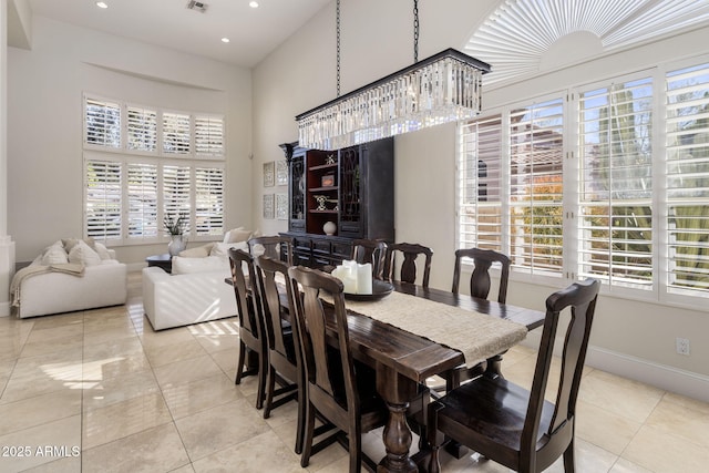 tiled dining space with a high ceiling and an inviting chandelier