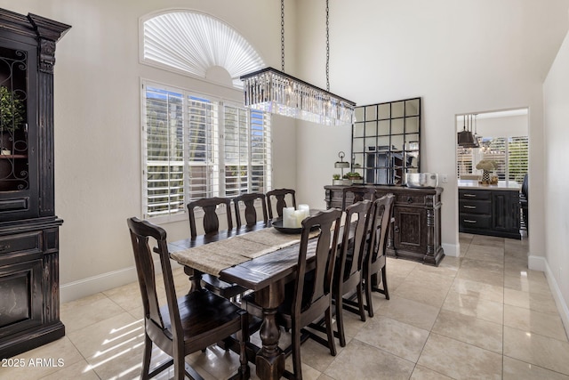 tiled dining area featuring a high ceiling, a chandelier, and a healthy amount of sunlight