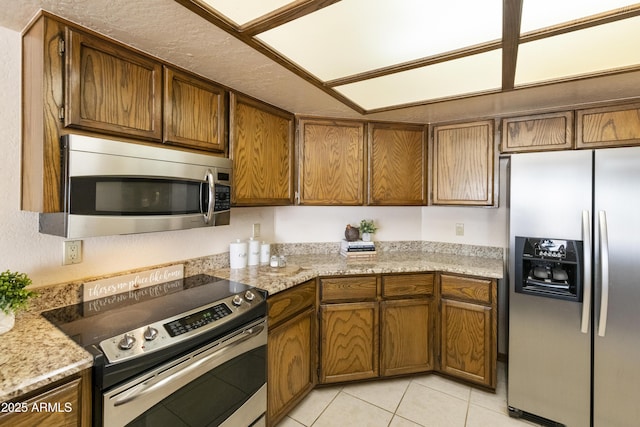 kitchen with light tile patterned flooring, appliances with stainless steel finishes, and light stone counters