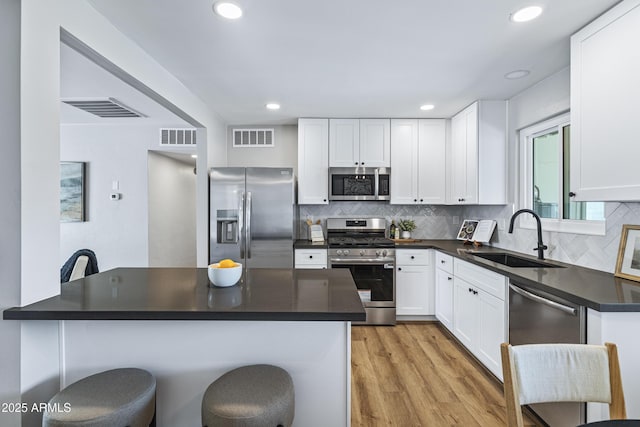 1359 E Nielson Ave, Mesa, AZ 85204 - kitchen featuring stainless steel appliances, dark countertops, a breakfast bar, light wood-type flooring, and white cabinetry