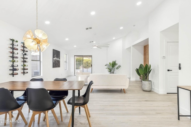 dining room featuring vaulted ceiling, light hardwood / wood-style flooring, and ceiling fan with notable chandelier