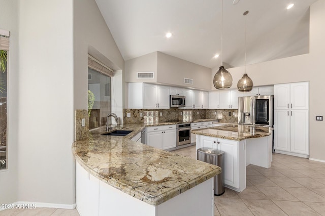 kitchen with appliances with stainless steel finishes, sink, light stone counters, a center island, and hanging light fixtures