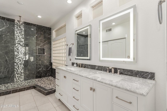 bathroom featuring tile patterned flooring, vanity, and tiled shower