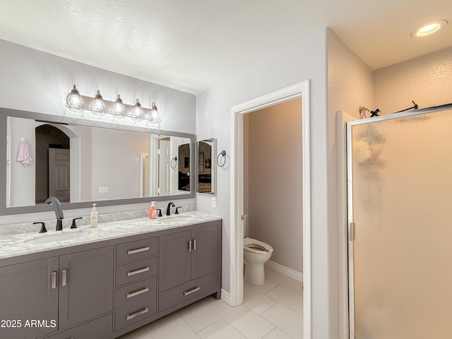 full bathroom featuring double vanity, a sink, toilet, and a shower stall