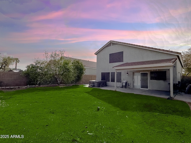 rear view of house featuring a patio area, a fenced backyard, a yard, and stucco siding