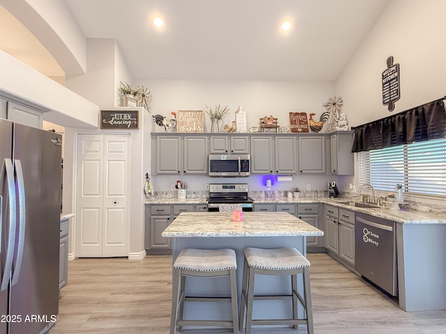 kitchen featuring light wood finished floors, appliances with stainless steel finishes, a sink, and gray cabinetry