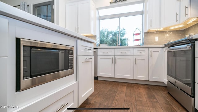 kitchen featuring dark wood-type flooring, white cabinets, stainless steel appliances, and tasteful backsplash