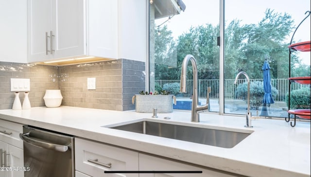 kitchen featuring stainless steel dishwasher, decorative backsplash, sink, and white cabinetry