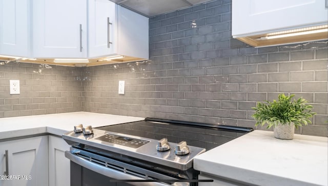 kitchen with stainless steel electric stove, white cabinets, and tasteful backsplash