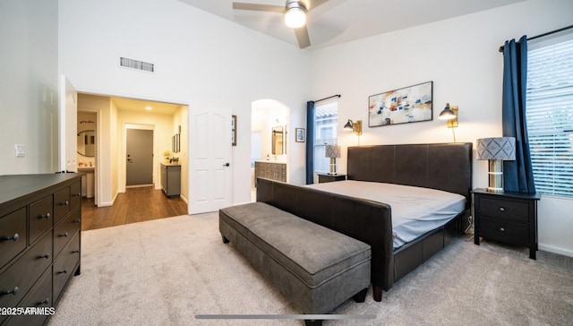 bedroom with ceiling fan, a towering ceiling, carpet floors, and ensuite bathroom