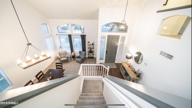 entryway with a high ceiling, wood-type flooring, and a chandelier