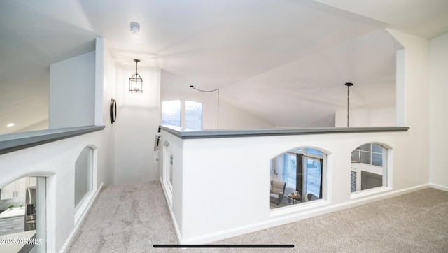 hallway featuring light carpet and lofted ceiling