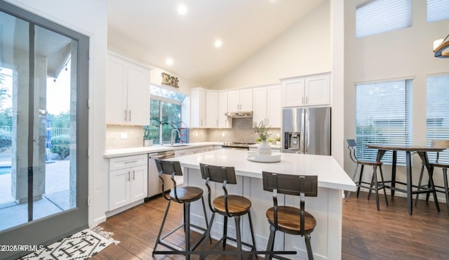 kitchen featuring a kitchen island, white cabinetry, stainless steel appliances, high vaulted ceiling, and dark hardwood / wood-style flooring