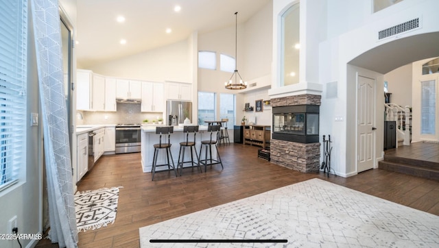 kitchen featuring white cabinets, appliances with stainless steel finishes, a kitchen island, decorative light fixtures, and tasteful backsplash