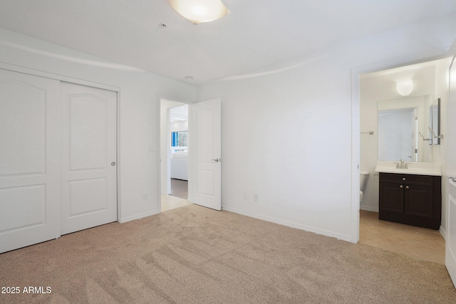 unfurnished bedroom with light colored carpet, connected bathroom, a closet, and sink