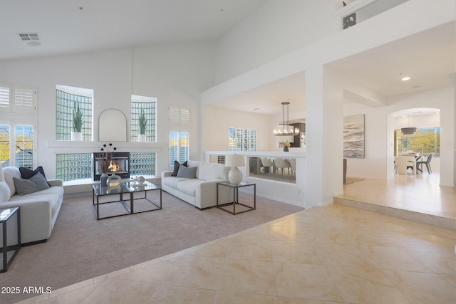 tiled living room featuring a notable chandelier, a high ceiling, and a tile fireplace