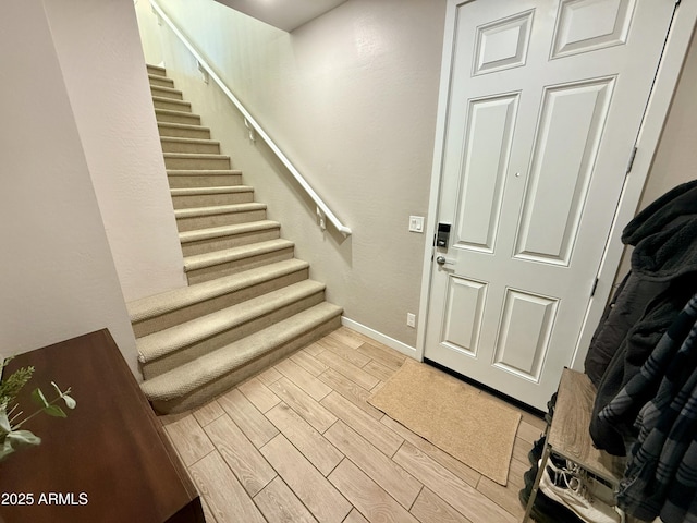 foyer entrance featuring stairs, baseboards, and wood tiled floor