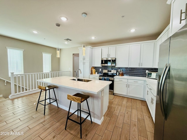 kitchen with wood finish floors, visible vents, backsplash, appliances with stainless steel finishes, and a sink