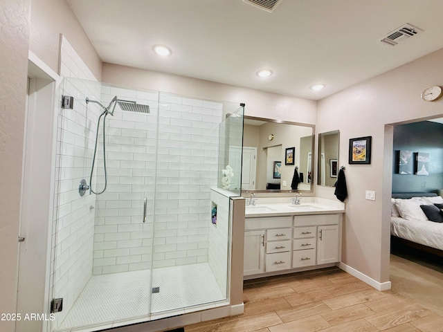 ensuite bathroom featuring double vanity, a stall shower, a sink, ensuite bath, and wood finished floors