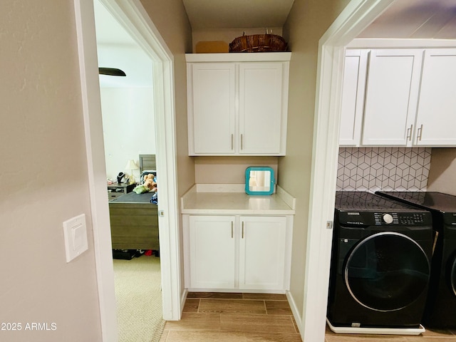washroom featuring washer / dryer, light wood finished floors, and cabinet space