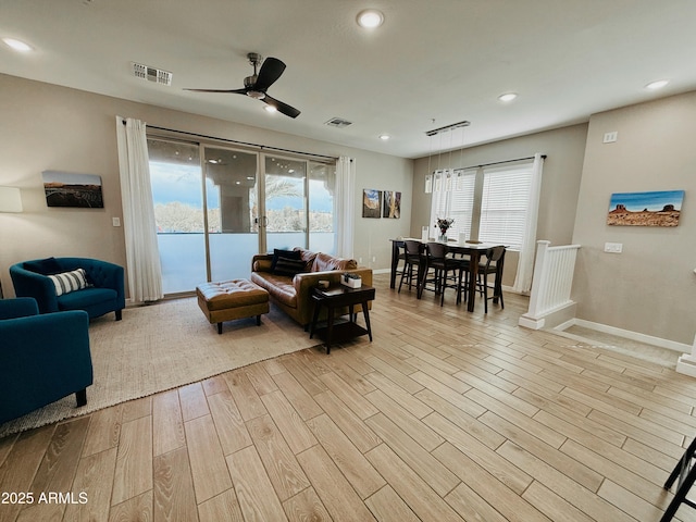 living room with baseboards, light wood finished floors, visible vents, and recessed lighting