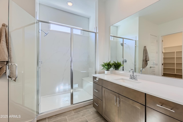 full bathroom featuring a stall shower, vanity, and a walk in closet