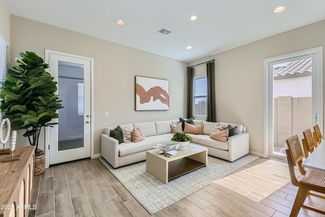 living area with recessed lighting, visible vents, a wealth of natural light, and wood finish floors