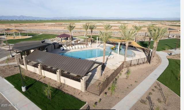 community pool with a patio area, a rural view, and fence