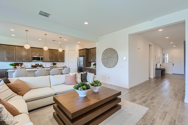 living room featuring recessed lighting, visible vents, baseboards, and light wood-style floors