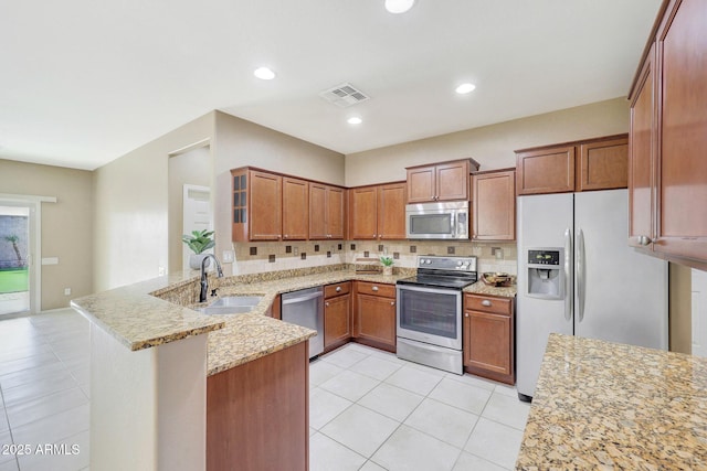 kitchen featuring sink, backsplash, light stone counters, kitchen peninsula, and stainless steel appliances